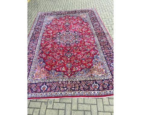 A hand knotted Persian Naja Fabad carpet. Red with foliate decoration - 330cms by 230cms