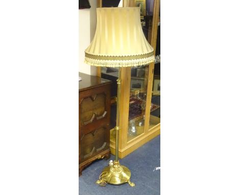 An Art Nouveau brass telescopic floor lamp with shade, raised on turned column support and circular platform base with three 