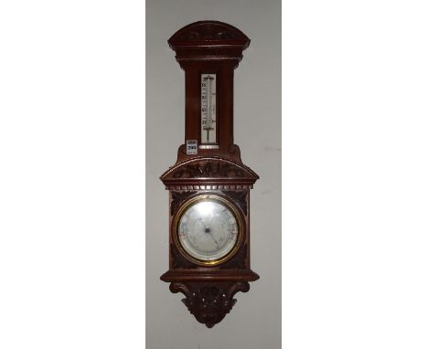 A mahogany aneroid wall barometer, (lacking glass) with carved floral decoration, 68.5cm high