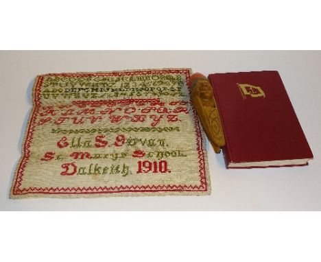 A pair of wooden novelty nutcrackers, with mask decoration, 21cm long, together with a needlepoint sampler worked by Ella S G