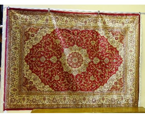 A machine made Keshan carpet, the central cream and gold floral medallion over red ground with allover gold foliate motifs, c