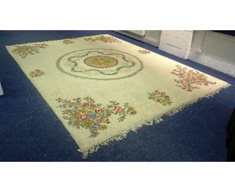 A large Eastern carpet, of plain design with circular floral wreath motif to centre over cream ground and floral panels to ea