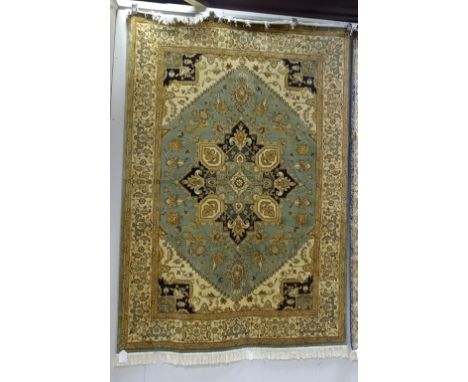 A machine made Heriz carpet, the central navy and gold floral medallion on green ground with cream and navy corners, allover 