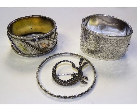 Two white metal bangles, one with allover floral engraved decoration, the other decorated with insects, owl and bird within b