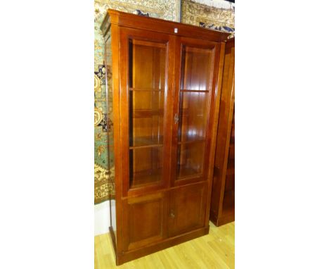 A large cherry wood bookcase by Grange Furniture, with two glazed doors enclosing a shelved interior above two panelled doors