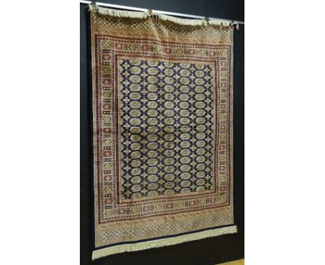 A machine made Eastern style carpet, the multiple guls to centre over navy panel with multiple multicoloured geometric border