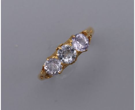 An unmarked, probably 18 ct gold, three stone possibly white sapphire ring. Ring Size N/O. 3.9 grammes total weight.