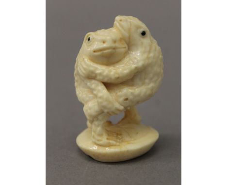 A carved bone netsuke formed as two toads. 5 cm high.