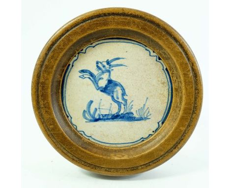 A Dutch Delft blue and white tile, circa 1640, painted with a gazelle on hind legs, 12cm diameter, in wooden frame 18cm diame