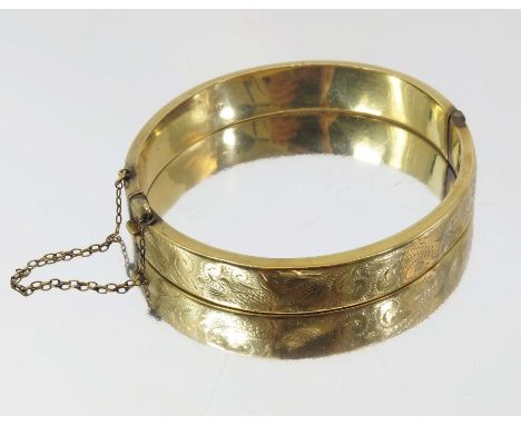 A 9 carat gold bangle, engraved with foliate scrolls to one side, 5.5cm inner diameter, 13.7g