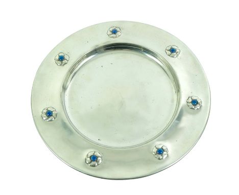 A Liberty and Co. pewter and enamelled charger, decorated with floral rosettes, the centres of each with blue enamel cabochon
