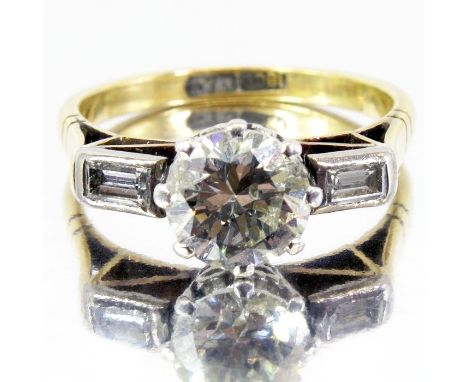 A diamond solitaire ring, the central brilliant cut stone flanked by baguettes, on 18 carat gold band, approx ring size K, st