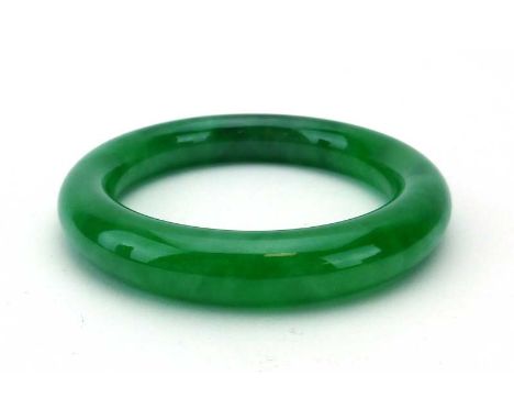 A green jade bangle, internal d. 5.9 cm CONDITION REPORT: Unknown if treated or natural 