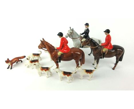 A Beswick ceramic hunting group consisting of two huntsmen on horseback, one huntswoman on horseback, six hounds and one fox.