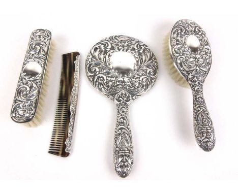 A silver backed dressing table set consisting of mirror, two brushes and comb, all having embossed foliate and green man deco