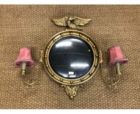 An Atsonea gilt framed circular wall mirror, having a pair of light sconces and an eagle finial