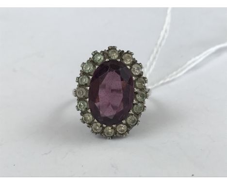 A vintage white-metal and paste cocktail ring, in a flower head cluster arrangement surrounding a central purple stone, 6.8g 