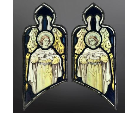 A pair of Angels, two trapezoidal stained, painted and leaded glass windows with ogee pediments, each 56cm by 23cm. * Provena