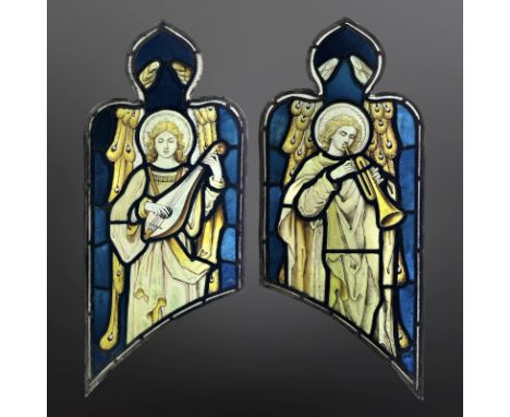 A pair of Angel Musicians, a lutenist and trumpeteer, two trapezoidal stained, painted and leaded glass windows with ogee ped