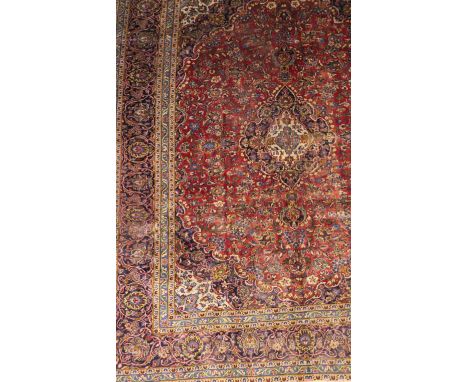 A Persian hand woven wool carpet, overall foliate design against a red ground with border stripes, 395 x 300cm