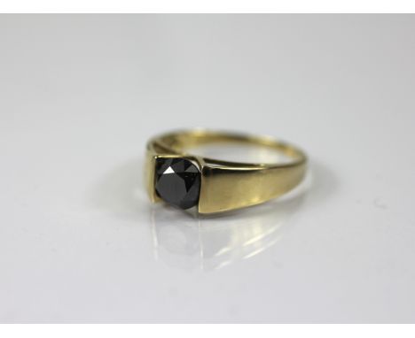A black diamond solitaire ring, the round brilliant black diamond (of approximately 1.50ct) suspension set in 9ct yellow gold