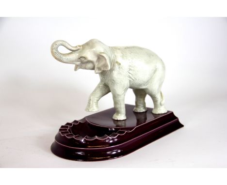 A Branksome China novelty elephant ash tray, the stepped puce base surmounted by a white glazed elephant modelled with raised