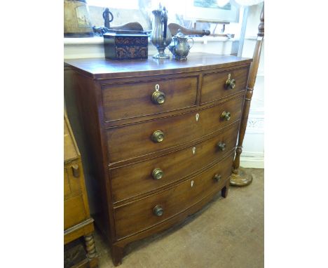 An English Regency Mahogany Bow Fronted Chest of Drawers, two short drawers over three long drawers, splayed feet, brass circ
