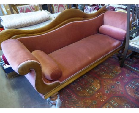 A Victorian Mahogany Sofa, the sofa having one swan shaped arm and back, on turned feet with casters, upholstered in coral ve