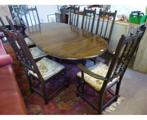 A Set of EIGHT Dark Oak Ercol Dining Room Chairs (6+2 carvers), together with an oval extending table.