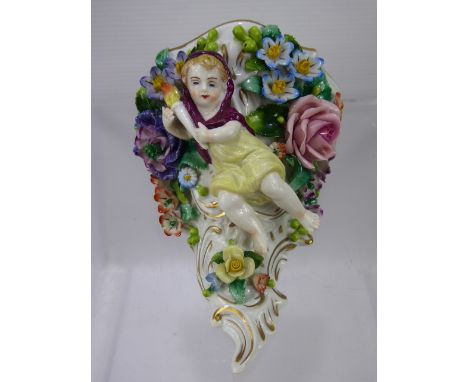 An Antique Sitzendorf Wall Mount, depicting a cherub carrying a torch surrounded by raised profuse floral decoration, approx 