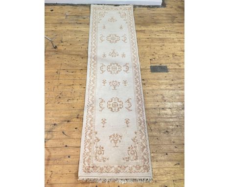 An Indian washed wool runner rug, the ivory field with floral motif and bordered 360cm x 95cm