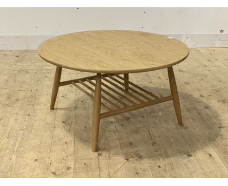 Ercol, a contemporary dry oak coffee table, the circular top raised on turned supports united by a magazine rack H43cm, D80cm