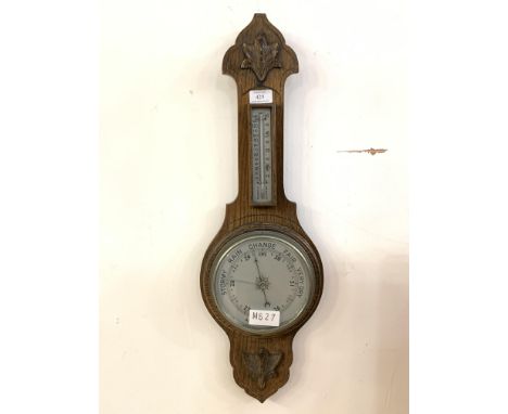A late 19th/early 20th century oak aneroid barometer and thermomter with silvered registers H68cm