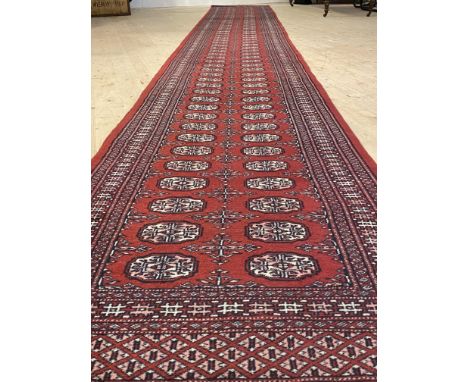 A bokhara runner rug, hand knotted, with two rows of guls within a multi line border 610cm x 84cm