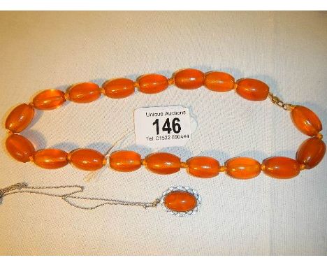 An amber necklace with 9ct gold clasp (approximately 50cm long) and and amber and enamel pendant in silver on a silver chain 