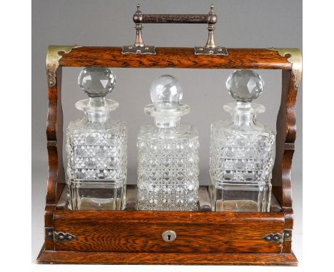 A late Victorian oak tantalus with silver plated mounts, fitted with three square decanters (a pair and an unmatched replacem