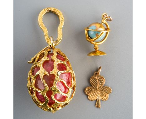 Two 9ct gold charms and a 9ct gold egg pendant. To include a three leaf clover charm, a globe charm with spinning blue enamel