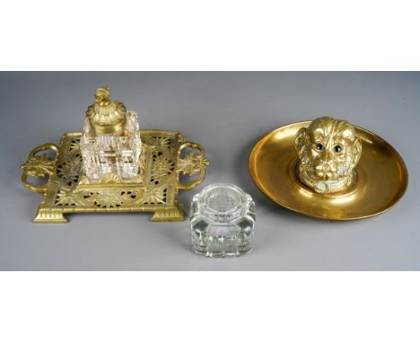 A late Victorian novelty brass inkwell in the form of a monkeys head with glass eyes, mounted on a circular brass tray, lacks