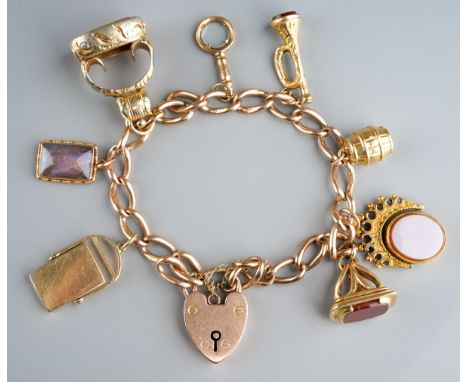 A 9ct gold bracelet with heart shaped clasp complete with eight charms (seals, trumpet, barrel etc)., total gross weight appr