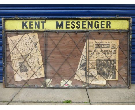 A wooden wall mounted newsagent's sign inset with an enamel strip "Kent Messenger" and three wire racks holding papers, 46 1/