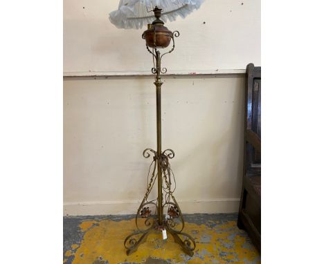 An Arts &amp; Crafts brass standard lamp on three scrolled legs, the oil lamp converted to electricity.&nbsp;