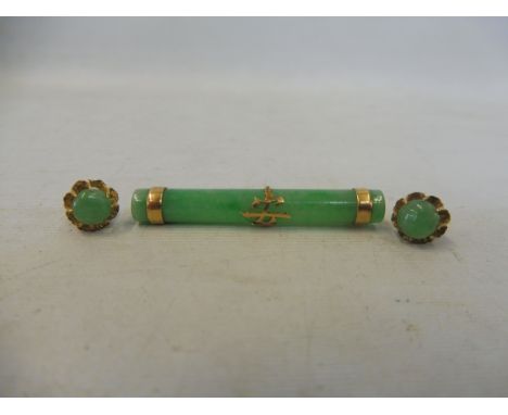 A jade cylindrical brooch mounted with three yellow metal bands plus a pair of jade and yellow metal earrings.&nbsp;