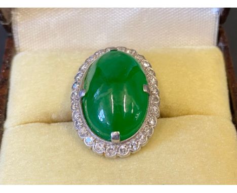 An 18ct gold and platinum jade ring surrounded by a band of diamonds, size F.