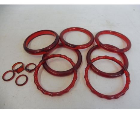 Seven ruby amber bangles and four rings.&nbsp;