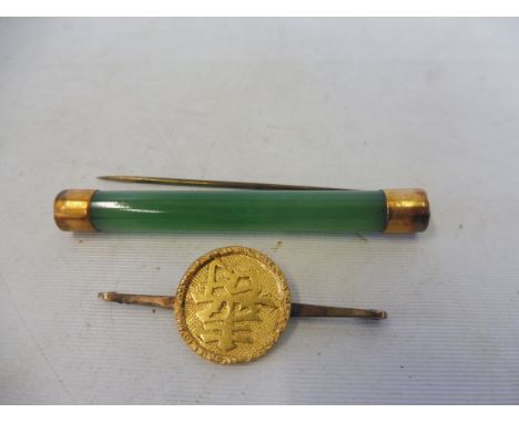 An Oriental yellow metal (probably gold) disc mounted on a 9ct gold pin brooch, approx. 3.1g plus an oriental jade cyclindric