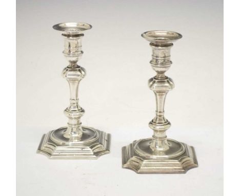Pair of George II silver candlesticks of double knop form standing on a stepped square base with canted corners and fixed sco
