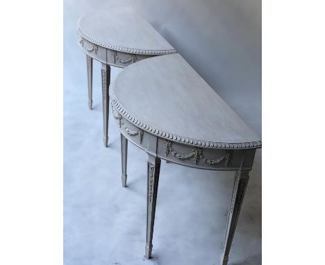 CONSOLE TABLES, a pair, George III design, Robert Adam style demi lune grey painted with ribbon swag frieze and square taperi