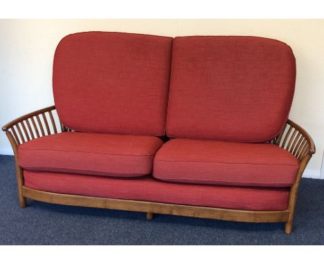 A massive Ercol three piece settee suite with red upholstered cushions. Est. £100 - £150.