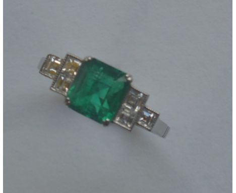 A good rare Art Deco emerald and diamond seven stone ring, the step cut stone with cut corners in platinum rubover mount. App