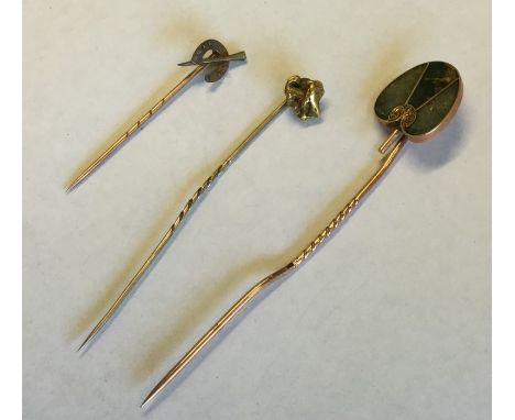 A high carat gold mounted stick pin in the form of a nugget together with two others. Approx. 7 grams. Est. £20 - £30.